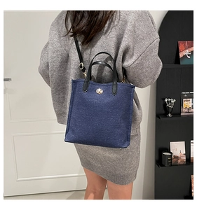 Detail of navy blue bucket bag with gold swivel lock and adjustable leather shoulder strap