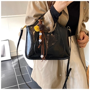 Détail d'un sac seau noir en cuir synthétique avec perles colorées porté par un mannequin