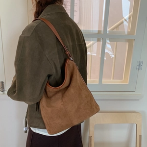Detailed view of the brown suede bucket bag texture on model with vintage matte finish