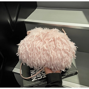 Gros plan d'un sac nuage en fausse fourrure rose avec détail de bandoulière en cuir