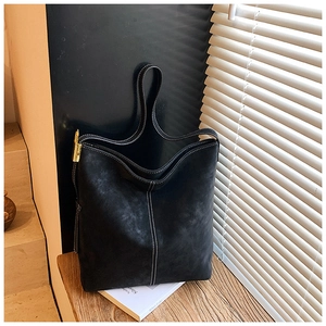 Detail of black tote bag featuring white contrast stitching and gold metal hardware