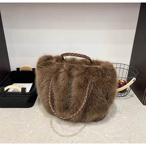 Detail der braunen Plüschtasche mit geflochtenen Griffen auf Marmoroberfläche