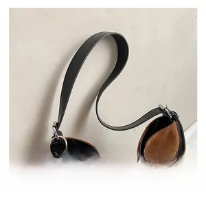 Close-up of brown suede tote bag with black leather strap and checkered bow charm