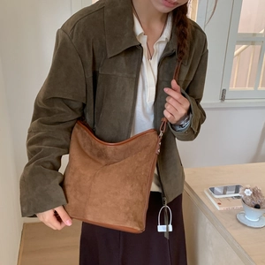 Close-up of vintage brown suede shoulder bag with dark leather piping on model