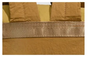 Detail eines karamellbraunen Nylon-Rucksacks mit verstärkten Nähten und Polstergurten