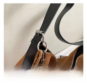 Detail of adjustable black leather strap with silver buckle on brown suede tote bag