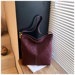 Nahaufnahme der lilafarbenen Veloursleder-Tasche mit Kontrastnaht und Goldverschluss