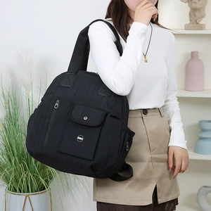 Detail of black quilted travel backpack showing multi-pocket design and nylon texture