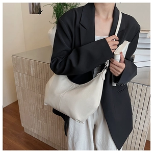 Détail d'un sac demi-lune en cuir blanc crème avec texture grainée et fermeture éclair