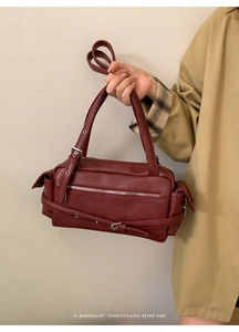 Detailed side view of deep red leather shoulder bag with buckle and pocket details
