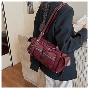 Chic burgundy shoulder bag styled with a dark blazer and white trousers in a studio setting
