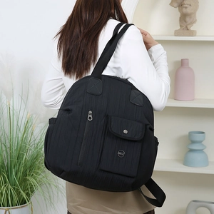 Detail of black quilted travel backpack with multiple pockets and nylon texture on model