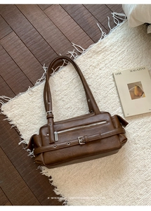 Detail of vintage brown shoulder bag with silver hardware on a cozy rug background