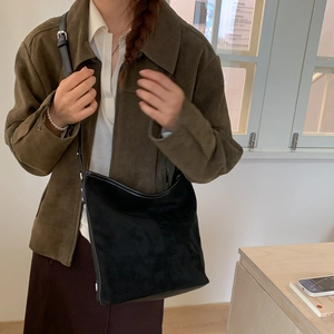 Close-up of black matte suede bucket bag with leather trim on model for vintage daily use