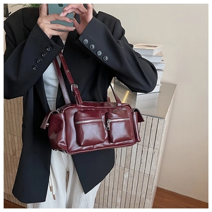 Detail of dark red glossy shoulder bag featuring double zip pockets and silver hardware