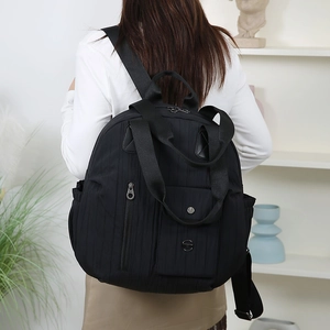 Detail of black quilted travel backpack with multiple pockets on a lifestyle model