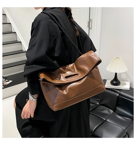 Detail of caramel brown tote bag with hollow handle and woven shoulder strap
