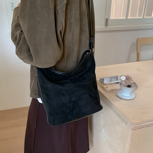 Minimalist black matte hobo bag shown from back view in a cozy cafe setting scene