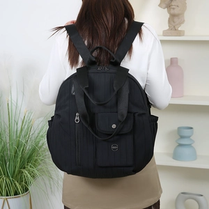Detail of black nylon travel backpack showing vertical quilting and metal zipper pockets