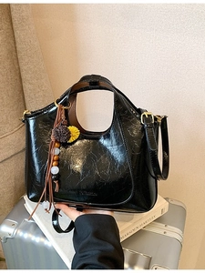 Sac bandoulière noir brillant minimaliste avec texture vintage et breloque bohème