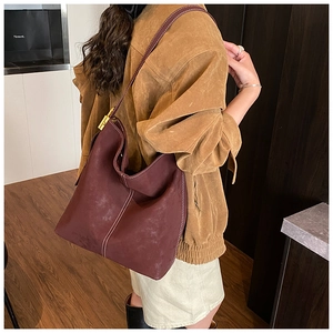 Detail view of large burgundy suede hobo bag with contrast stitching and gold buckle