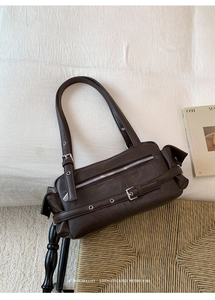 Detail of dark brown leather shoulder bag with silver eyelets and retro zipper features