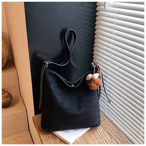 Close-up of a black matte suede tote bag featuring a cute brown plush bear charm detail