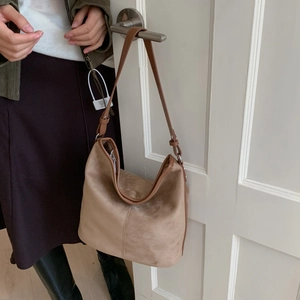Detail view of khaki frosted hobo bag hanging on a door handle showing texture and strap