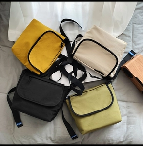 Dettaglio dei borselli a tracolla in giallo, beige, nero e verde oliva disposti in piano