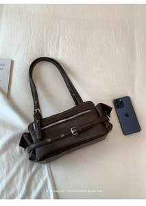 Detail view of dark brown pillow bag featuring retro metal buckle and side zip pocket