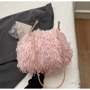 Détail du sac à bandoulière en fausse fourrure rose avec texture pelucheuse et boule dorée