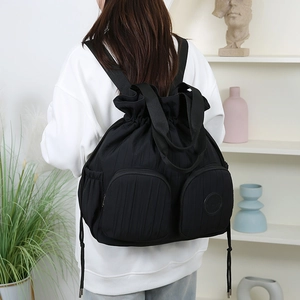 Detail eines schwarzen Nylon-Rucksacks mit Faltenoptik, Kordelzug und Reißverschlusstaschen
