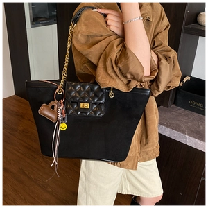 Detail of black matte tote bag featuring quilted leather flap and gold chain strap