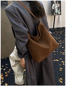 Detail of vintage brown suede tote bag with white contrast stitching on wide strap