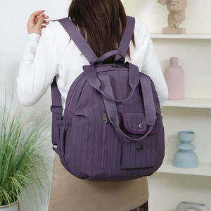 Rear view of model wearing a deep purple waterproof backpack with vertical stripes