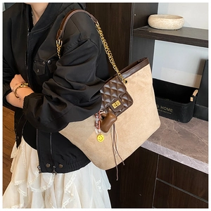 Detail of canvas tote bag with brown leather pocket and gold chain shoulder strap