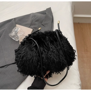 Détail du sac à main en peluche noire avec bandoulière en cuir et détails dorés