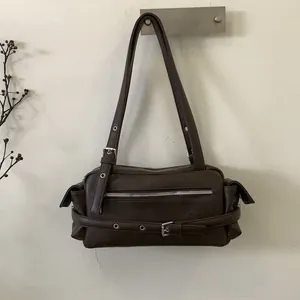 Detail of dark brown leather pillow bag with silver metal eyelets and zipper accents