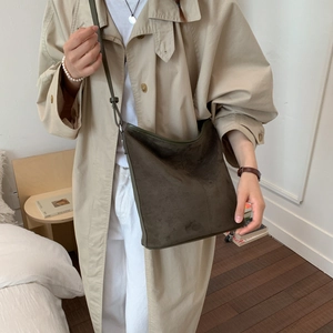 Chic olive suede bucket bag shown worn with a beige trench coat for a vintage commute look