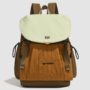 Detail eines Farblock-Rucksacks mit orangefarbenem Stoff und grünem Klappdeckel-Design