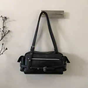Detail view of black faux leather shoulder bag with silver zippers and buckle accents