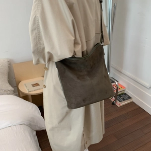 Side view of a vintage brown suede hobo bag worn by a model in a minimalist setting