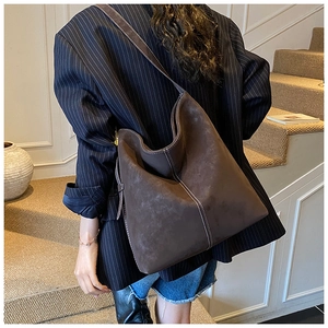 Detail of dark brown suede shoulder bag with white contrast stitching and wide strap