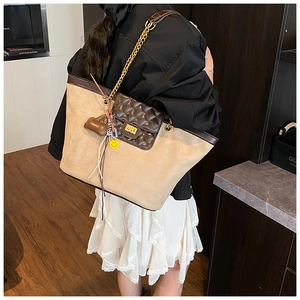 Detail view of large beige suede tote bag with brown leather accents and gold chain strap