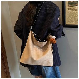 Khaki suede hobo bag shown on shoulder featuring a cute brown plush bear charm