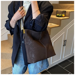 Detail of dark brown suede tote bag featuring contrast stitching and gold metal lock