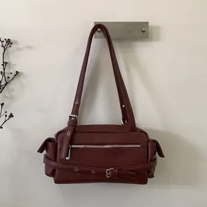 Macro detail of wine red hobo bag showing faux leather texture and silver buckle strap