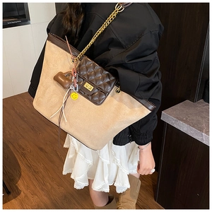 Detail of contrast suede tote bag with quilted front pocket and gold chain strap