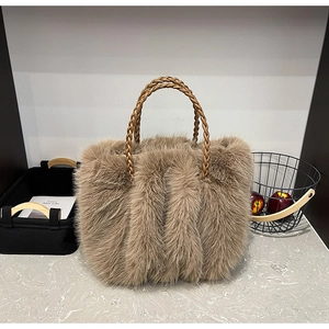 Detailaufnahme der Plüschtasche aus Kunstpelz mit braunem Flechtgriff auf grauem Grund