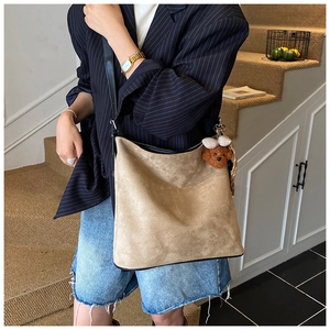 Detail of khaki suede tote bag with large capacity and cute brown plush bear charm